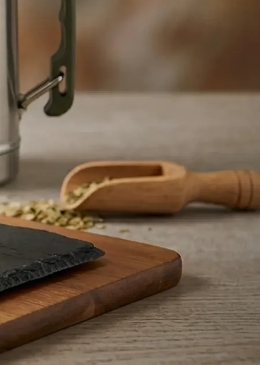 Cucharita dosificadora de madera con yerba sobre tabla